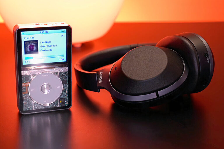 iPod connected to large black headphones on a red background.